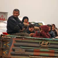 Members of a family fleeing with their belongings pass through the town of Hazano in the northern Syria countryside of Idlib Wednesday, fleeing northward amid an ongoing regime offensive. | AFP-JIJI