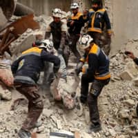 Rescue workers known as the White Helmets remove the body of a victim from the rubble of a building, hit during an airstrike by pro-regime forces on the rebel-held town of Ariha in the northern countryside of Syria\'s Idlib province on Wednesday. | AFP-JIJI