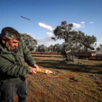 A Syrian rebel fighter remotely fires a rocket from a truck-mounted launcher at a position in the countryside of Idlib toward regime forces positions in the southern countryside of Syria\'s Aleppo province on Monday. | AFP-JIJI
