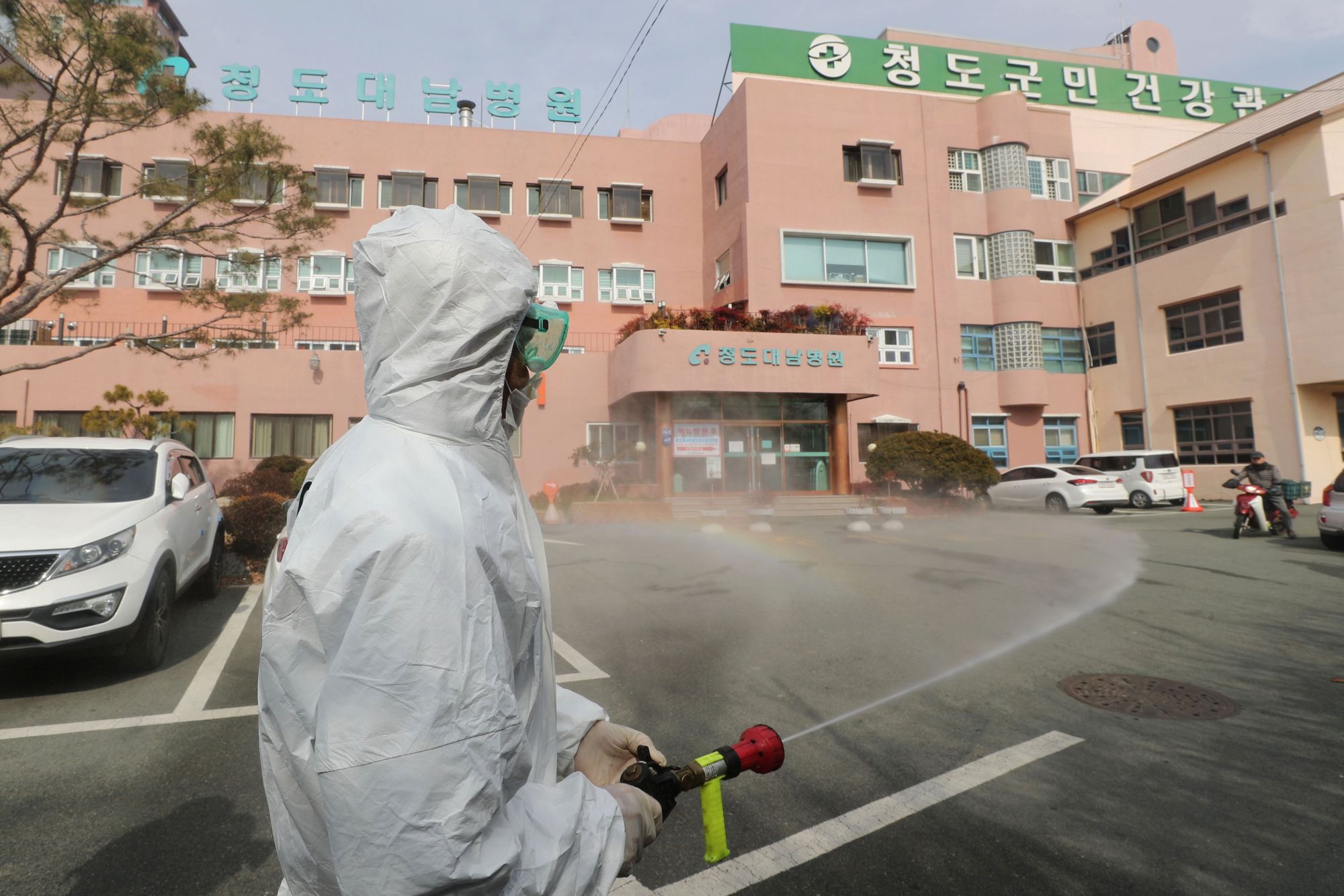 A South Korean health official sprays disinfectant in front of a hospital where 16 infections have now been identified with COVID-19 in Cheongdo County near Daegu on Friday. | AFP-JIJI