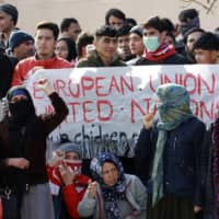 Migrants shout slogans during a protest in Mytilene port, on the northeastern Aegean island of Lesbos, Greece, on Tuesday. | MANOLIS LAGOUTARIS / INTIME NEWS / VIA AP