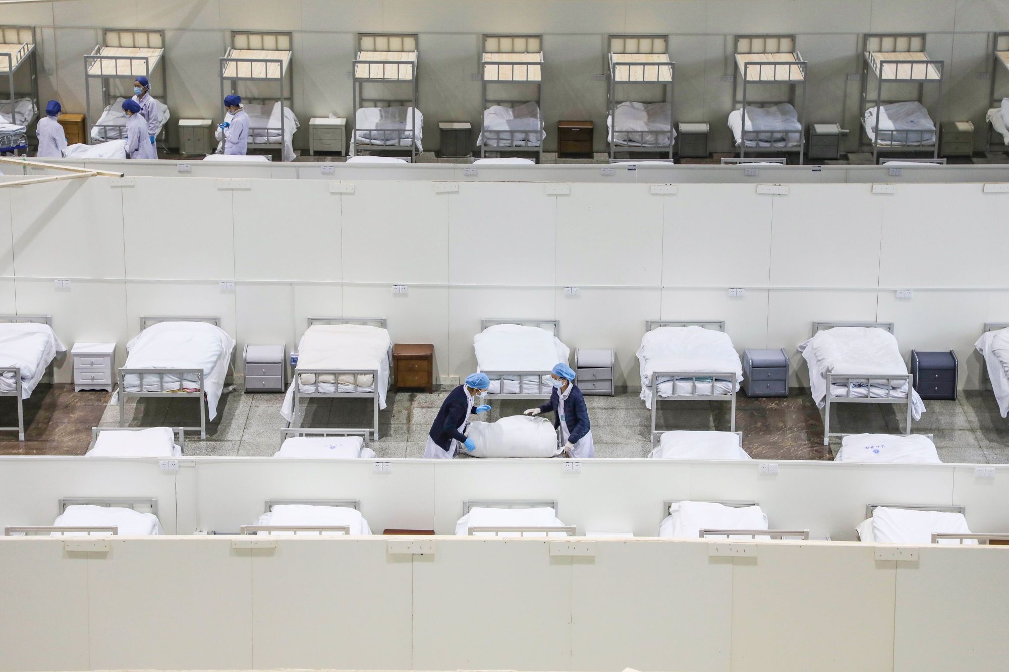 Staff members set up beds for patients displaying mild symptoms of the novel coronavirus infection at an exhibition center that has been converted into a hospital in Wuhan, China, on Thursday. | AFP-JIJI