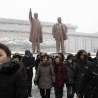 North Koreans visit the statues of the late leaders Kim Il Sung (left) and Kim Jong Il on Mansu Hill in Pyongyang on Sunday to commemorate the 78th birthday of Kim Jong Il. | AP