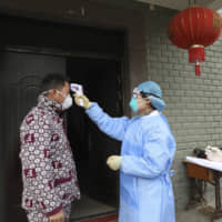 Community health workers in Hangzhou, in eastern China\'s Zhejiang province, check the temperature of a person who recently returned from Hubei province on Monday. | AP