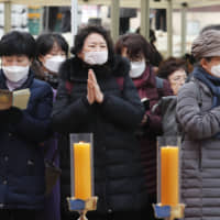 People wearing face masks pray at the Jogyesa Buddhist temple in Seoul on Sunday. South Korea will bar entry by foreigners who have visited China\'s Hubei province, the epicenter of a new coronavirus outbreak, the country\'s prime minister said Sunday, a media report said. | AP