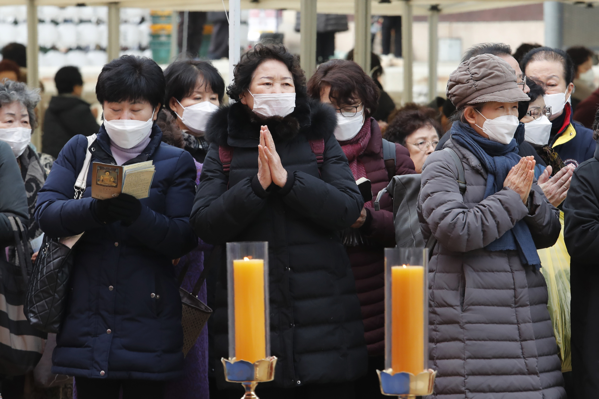 People wearing face masks pray at the Jogyesa Buddhist temple in Seoul on Sunday. South Korea will bar entry by foreigners who have visited China's Hubei province, the epicenter of a new coronavirus outbreak, the country's prime minister said Sunday, a media report said. | AP