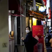 A resident of Daegu, South Korea, waits for her food on the Dongseong-ro shopping street on Friday. | REUTERS