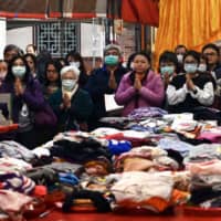People wearing protective masks pray beside their clothes laid out on a table at a Taoist Baoan temple in Taipei on Tuesday. | AFP-JIJI