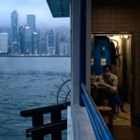 A worker wears a face mask as a preventative measure against the COVID-19 coronavirus as he takes a rest in a storeroom of a public toilet in Hong Kong\'s Tsim Sha Tsui district on Wednesday. City planners and physicians say densely packed urban centers are particularly vulnerable to deadly disease outbreaks and may need a redesign. | AFP-JIJI