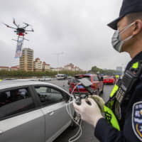 A police officer operates a drone near an expressway toll station in Shenzhen, in southern China\'s Guangdong Province, on Tuesday. | AP