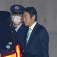 Tsukasa Akimoto, a House of Representative member indicted on charges of taking bribes from a Chinese firm in relation to casino matters, gets ready to enter a car after being released from the Tokyo Detention House. | KYODO