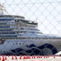 The Diamond Princess cruise ship is seen  through a fence at Daikoku Pier Cruise Terminal in Yokohama on Feb. 11. | REUTERS