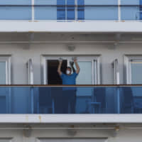 A passenger exercises using two water bottles on Wednesday aboard the quarantined Diamond Princess cruise ship in Yokohama. | AP