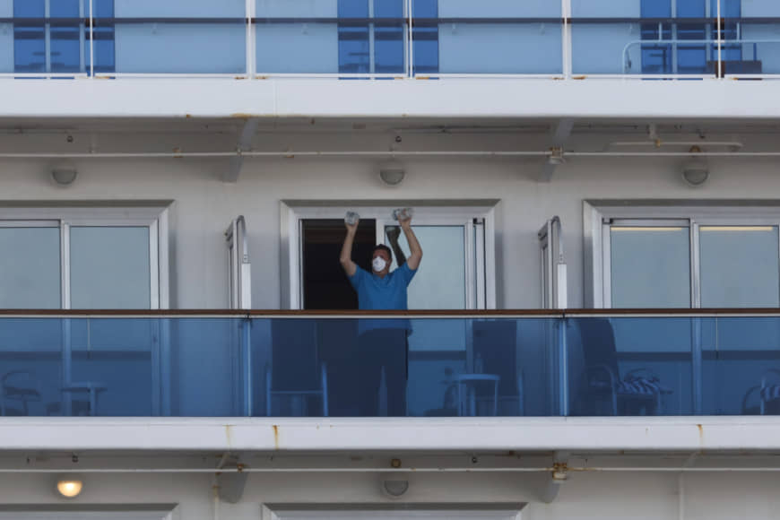 A passenger exercises using two water bottles on Wednesday aboard the quarantined Diamond Princess cruise ship in Yokohama. | AP