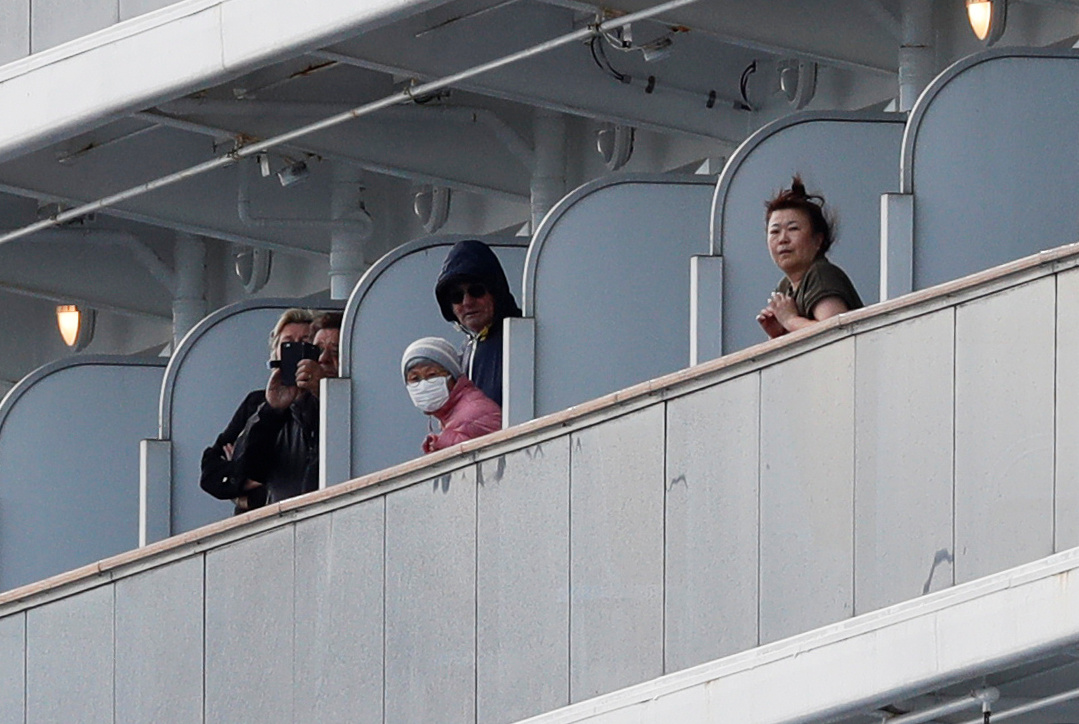 Passengers look out from their cabins as the cruise ship Diamond Princess, where 10 people on the ship tested positive for coronavirus Thursday, arrives at Daikoku Pier Cruise Terminal in Yokohama the same day. | REUTERS