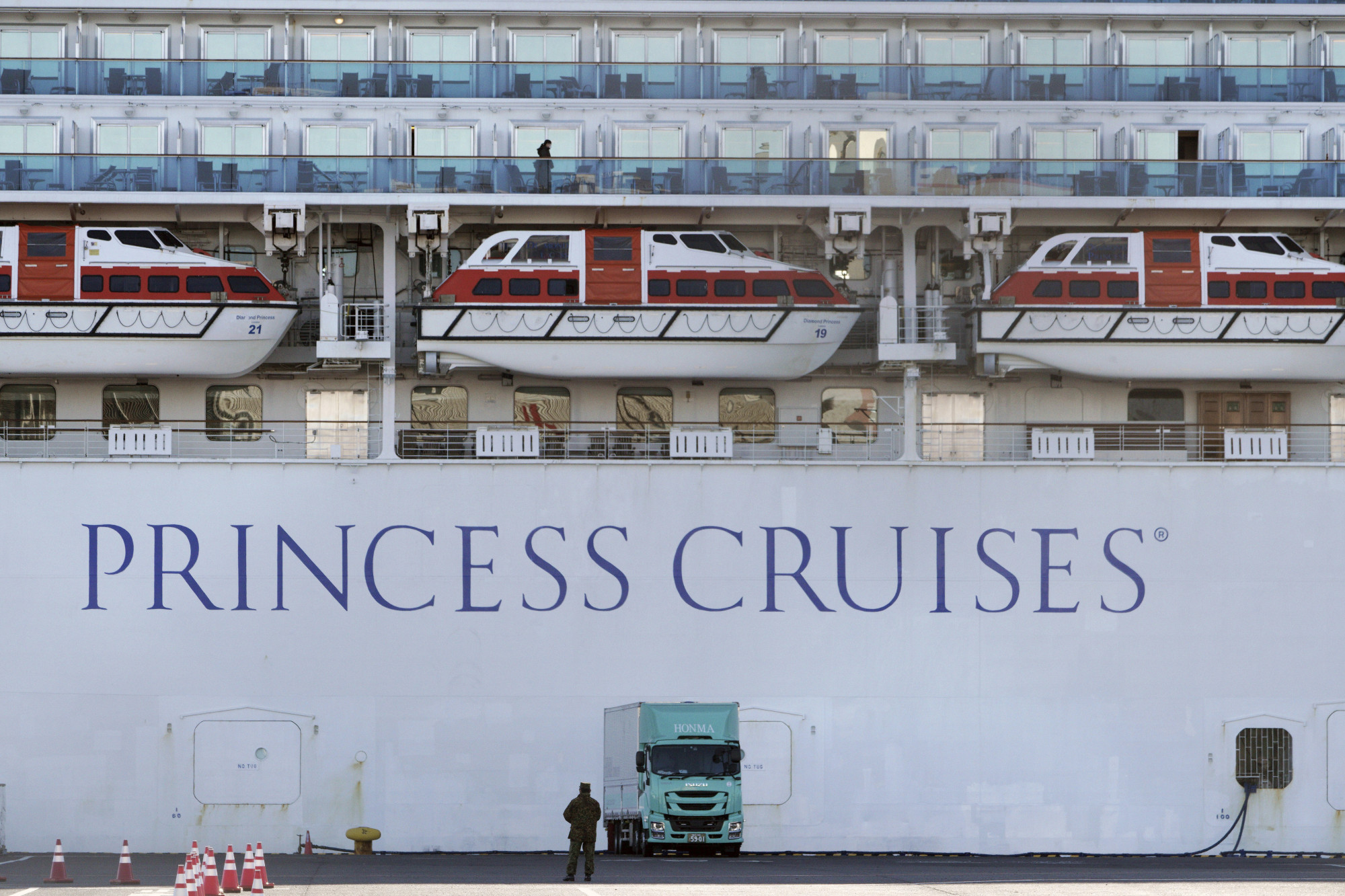 A passenger looks out from a cabin balcony on the quarantined cruise ship Diamond Princess in Yokohama port on Sunday. | AP