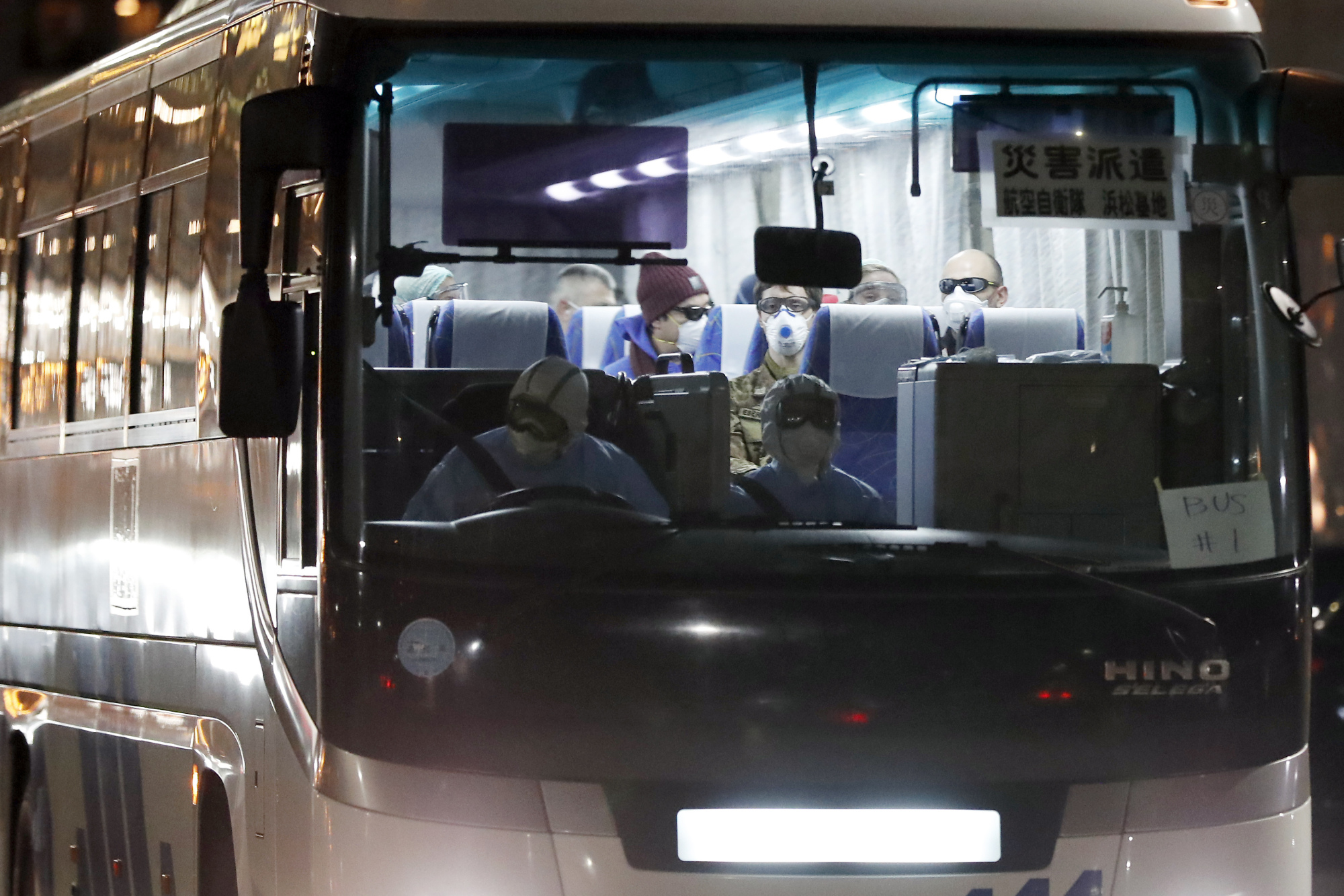A bus carrying foreign passengers from the quarantined Diamond Princess cruise ship leaves Yokohama port on Friday. Israel's health ministry said the same day that an Israeli woman who was a passenger aboard the ship tested positive upon return to her home country. | AP