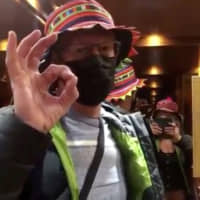 Diamond Princess cruise ship passenger Chris Peck, who shared a room with Vicki Presland (taking video) gestures in the elevator while disembarking after a two-week quarantine caused by the COVID-19 outbreak, in Yokohama, on Wednesday. This still image was taken from a social media video. | VICKI PRESLAND VIA REUTERS