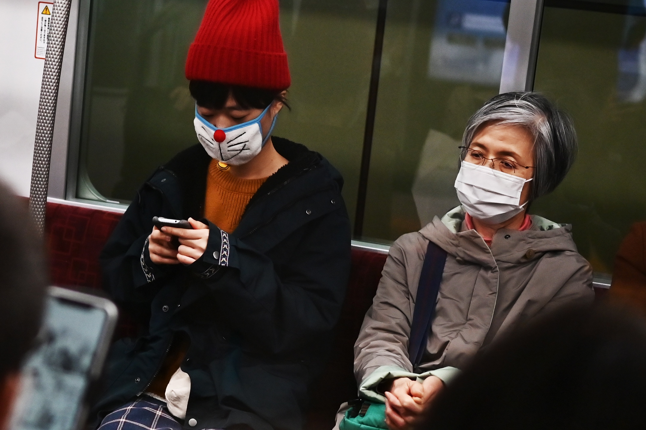 People wearing face masks travel on a train in Tokyo on Tuesday. | AFP-JIJI