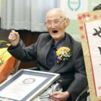 Chitetsu Watanabe poses with his own calligraphy that reads \"world No. 1\" in Joetsu, Niigata Prefecture, on Feb. 12, when he received a certificate identifying him as the world\'s oldest man at age 112. | POOL / VIA KYODO