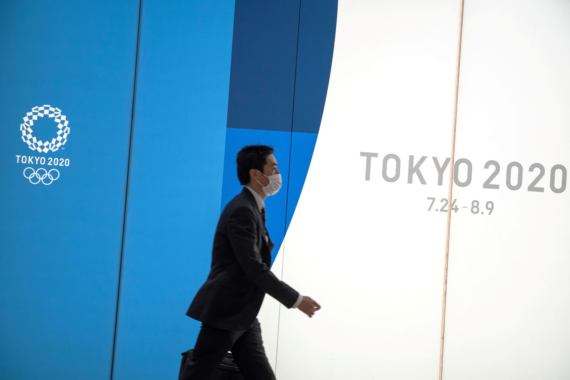 A man wearing a protective mask walks past a Tokyo 2020 billboard near Shinjuku Station in Tokyo. With Friday marking exactly 147 days until the opening ceremony for the Olympics on July 24, a scene from the 1988 post-apocalypse anime 'Akira' has become a talking point on social media. | REUTERS