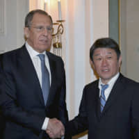 Foreign Minister Toshimitsu Motegi and his Russian counterpart, Sergey Lavrov, shake hands at a meeting in Munich on Saturday. | FOREIGN MINISTRY / VIA KYODO