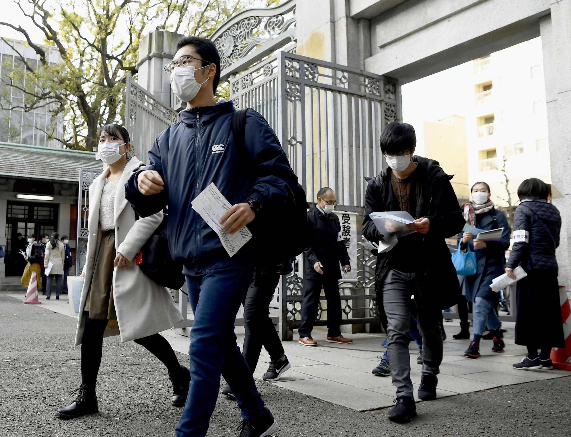 Students wearing masks arrive at the University of Tokyo to take entrance exams on Tuesday. | KYODO