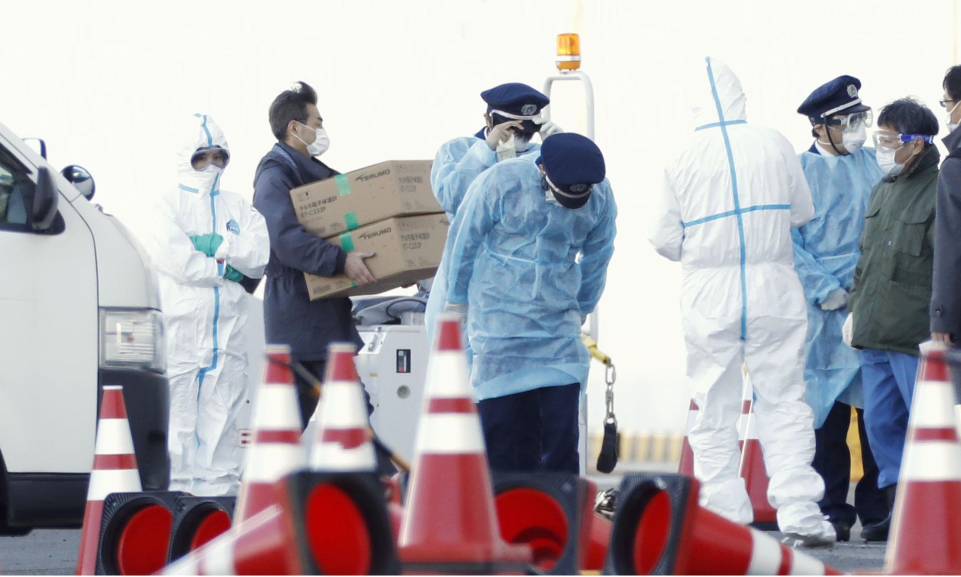 Officials carry supplies for the Diamond Princess cruise liner docked at Yokohama port on Thursday. Forty-one more people on the quarantined ship have tested positive for the new coronavirus, it was announced Friday. | KYODO