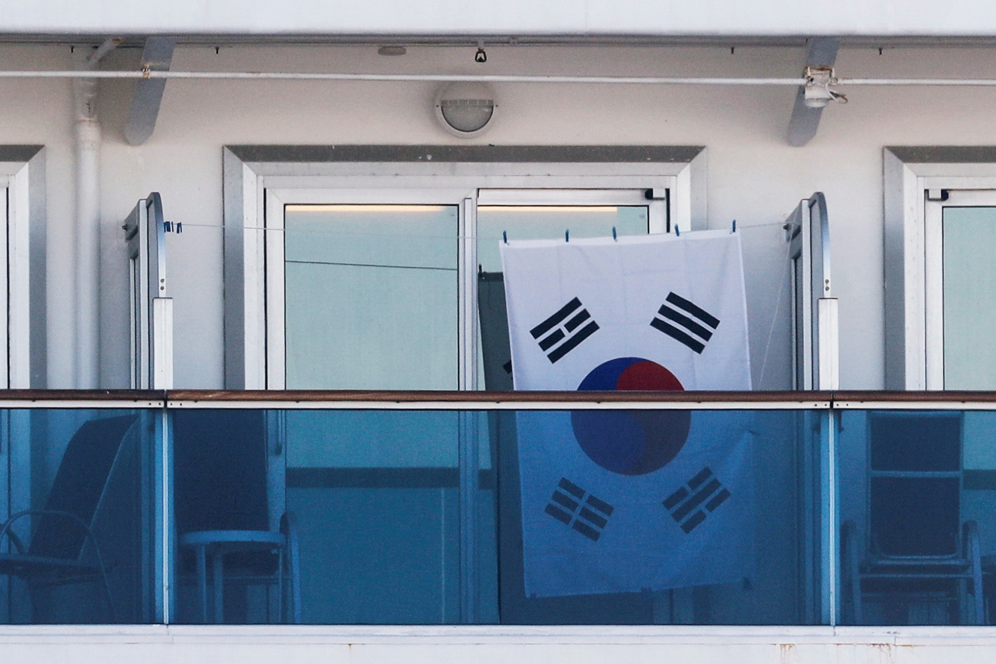 A South Korean flag is seen on the balcony of a cabin on the cruise ship Diamond Princess, as the vessel's passengers continue to be tested for coronavirus, at Daikoku Pier Cruise Terminal in Yokohama, on Thursday. | REUTERS
