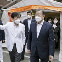 Wearing a face mask, South Korean President Moon Jae-in visits a hospital in Seoul last week where people infected with the coronavirus are hospitalized. | SOUTH KOREAN PRESIDENTIAL OFFICE / VIA KYODO