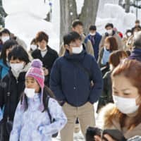 Visitors wear masks at the annual Sapporo Snow Festival in Hokkaido on Tuesday. | KYODO