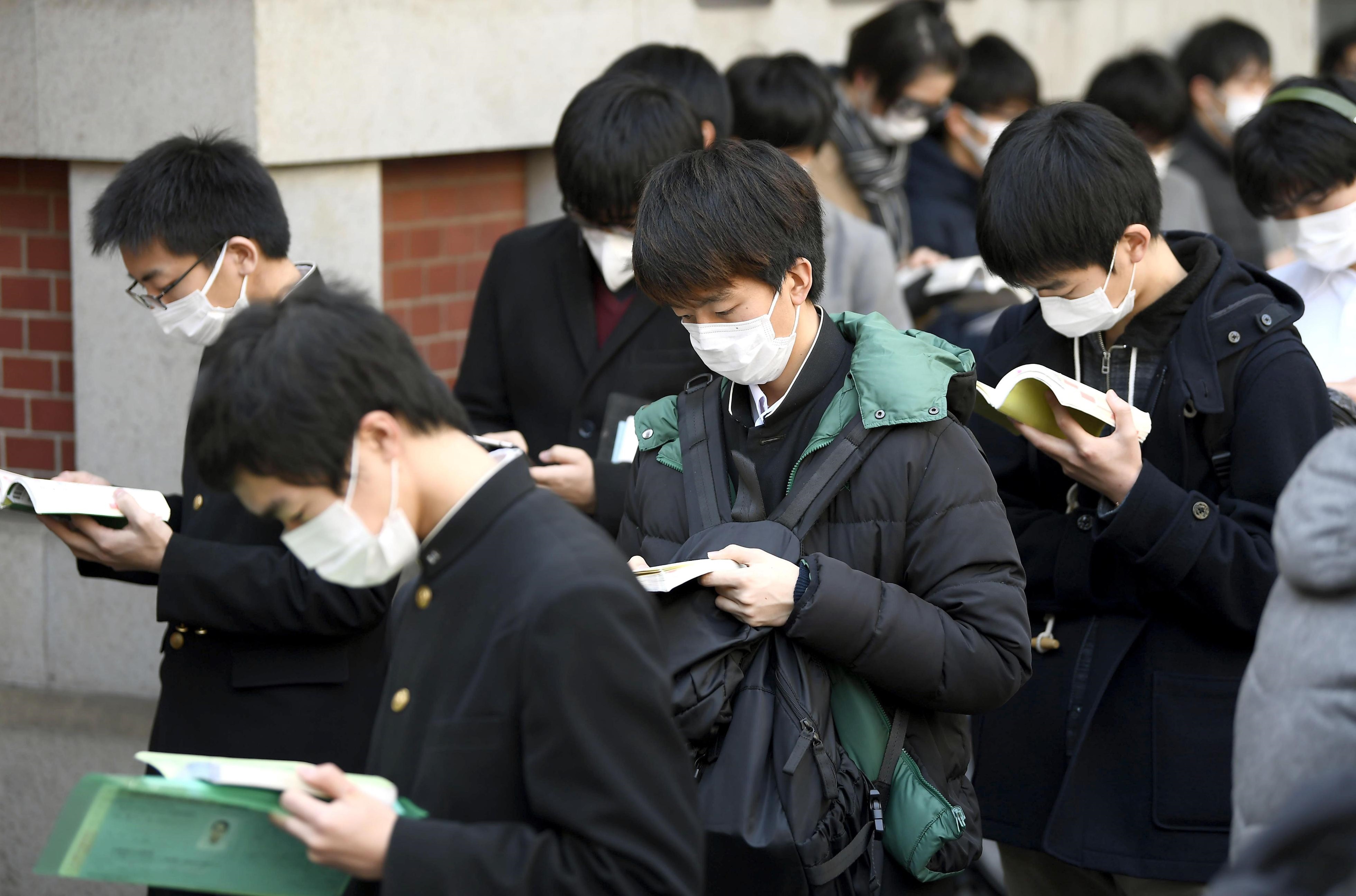Students wearing masks make final preparations as they head to the University of Tokyo for entrance exams on Tuesday.  | KYODO