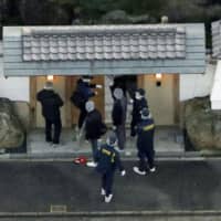 Police examine the entrance at the residence of Kiyoshi Takayama, deputy leader of the Yamaguchi-gumi, on Sunday in Kuwana, Mie Prefecture. A man was arrested for allegedly firing a gun at the main gate earlier the day. | KYODO
