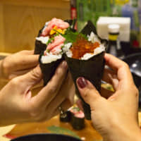 Tasting the best of Japan: Arigato Japan Food Tours participants hold up colorful, seafood-laden temaki (sushi hand roll). | CREATIVE COLLECTIVE