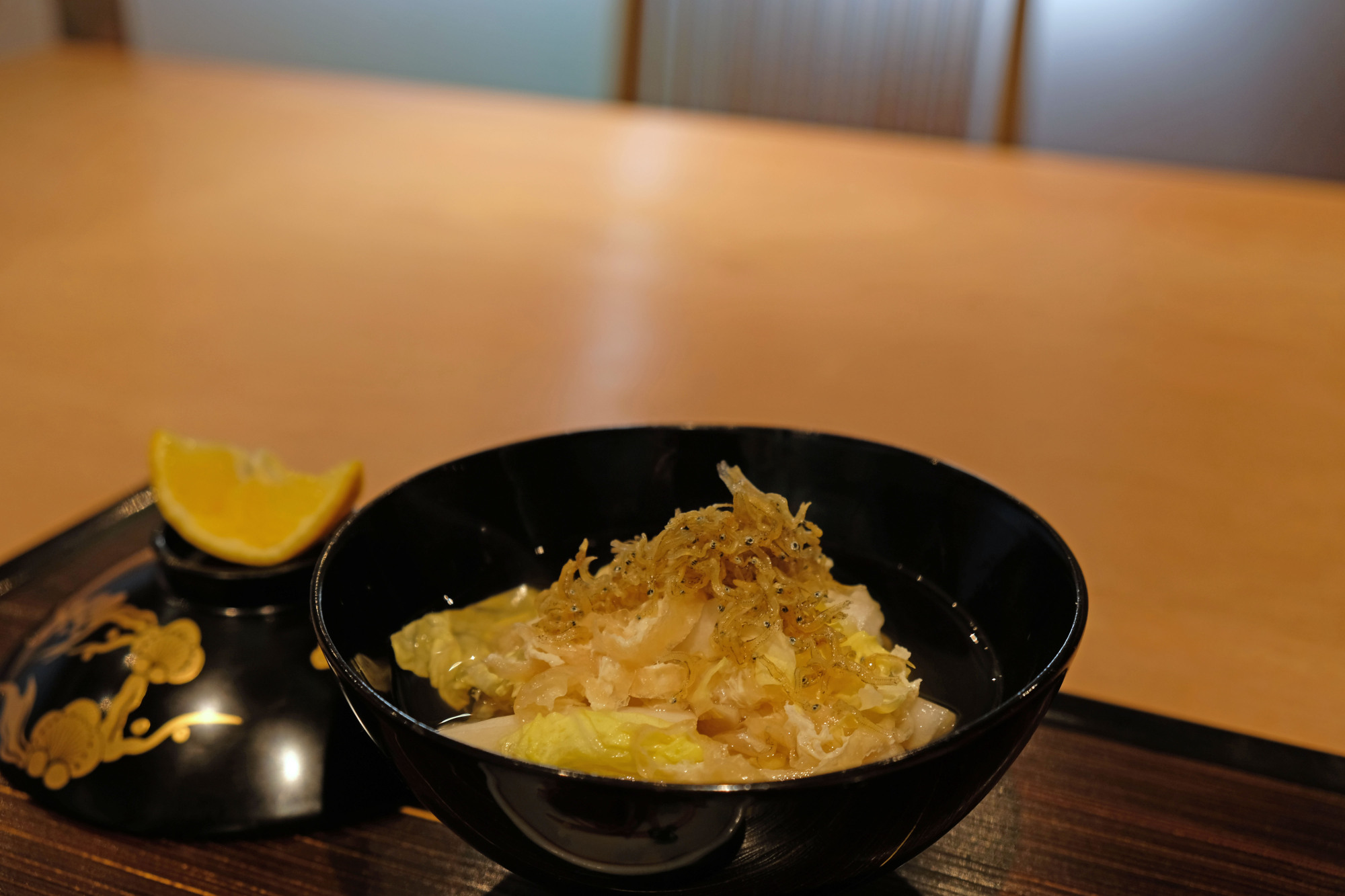Seasonal flair: One meal at Nagumo opens with a delicate bowl of cabbage and small, dried fish with a wedge of fragrant sudachi citrus on the side. | CLAIRE WILLIAMSON