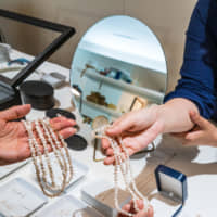 A clerk at Jinbo Pearls in Otsu shows a customer jewelry made from Lake Biwa pearls. | PHILIPPE VOISIN