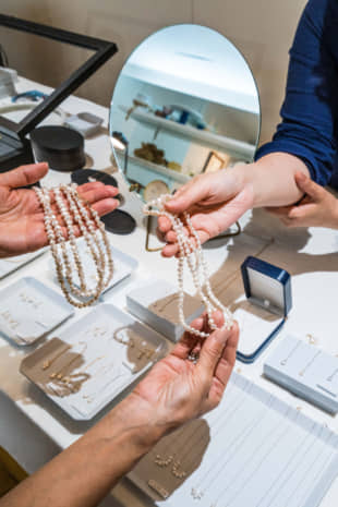 A clerk at Jinbo Pearls in Otsu shows a customer jewelry made from Lake Biwa pearls. | PHILIPPE VOISIN