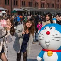 Women take a photo with a Doraemon figure in Yokohama. | GETTY IMAGES
