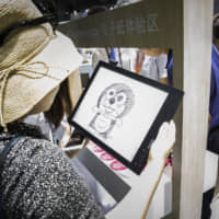 A woman looks at a sketch of the character Doraemon at an exhibition in Shanghai in 2018. | BLOOMBERG