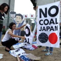 People prepare for a rally in Kobe last June 27 to protest Japan’s support for new coal-fired power generation projects.  | BLOOMBERG