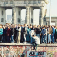 People stand on the Berlin Wall near the Brandenburg Gate in Berlin on Nov. 9, 1989. East and West Germany united on Oct. 3, 1990, after more than 45 years of division. | SUE REAM