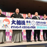 Ozeki Takakeisho (left) and yokozuna Hakuho (second from left) and Kakuryu (right) pose for photos during an event at Ryogoku Kokugikan on Tuesday. | DAN ORLOWITZ