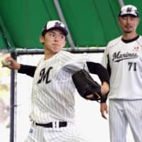 Marines rookie Roki Sasaki delivers as pitching coach Masato Yoshii watches during a bullpen session on Thursday in Ishigaki, Okinawa Prefecture. | KYODO