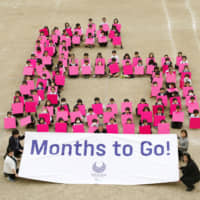 Third-grade students from Ariake Nishi Gakuen in Tokyo line up to create a giant No. 6 to mark the six-month countdown to the 2020 Paralympics on Tuesday. | KYODO