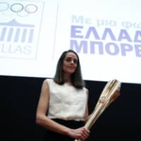 Greek actress Xanthi Georgiou holds the torch for the 2020 Tokyo Olympics during a presentation in Athens on Monday. | AP