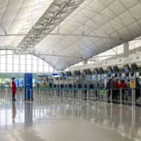 Passengers wait at check-in counters for Cathay Pacific Airways at Hong Kong International Airport on Thursday. | BLOOMBERG