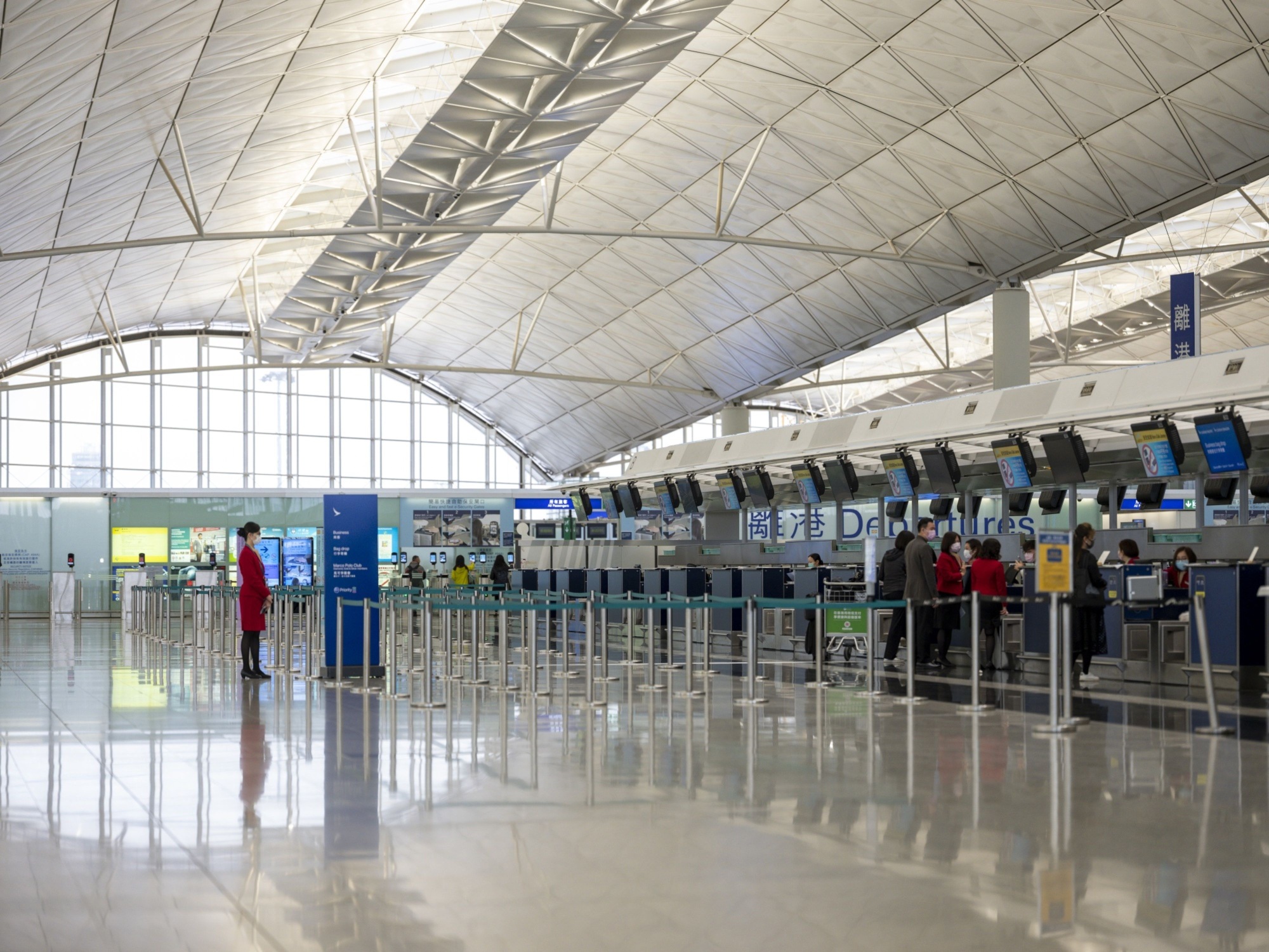 Passengers wait at check-in counters for Cathay Pacific Airways at Hong Kong International Airport on Thursday. | BLOOMBERG