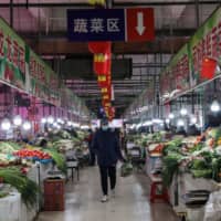 A customer looks at vegetables at a market in Shenyang in northeastern China on Monday. A survey shows that Chinese consumer sentiment has remained relatively strong compared with that in many countries hit by the coronavirus outbreak, including Japan. | AFP-JIJI