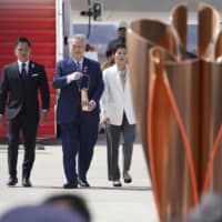 Tokyo 2020 Olympics chief Yoshiro Mori (third from left), followed by three-time Olympic gold medalists Tadahiro Nomura and Saori Yoshida, carries the Olympic flame during the arrival ceremony at Japan Air Self-Defense Force Matsushima Base in Higashimatsushima in Miyagi Prefecture on Friday. | AP