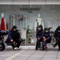 Security guards wear protective face masks outside a shopping mall in Shanghai on Sunday. | REUTERS